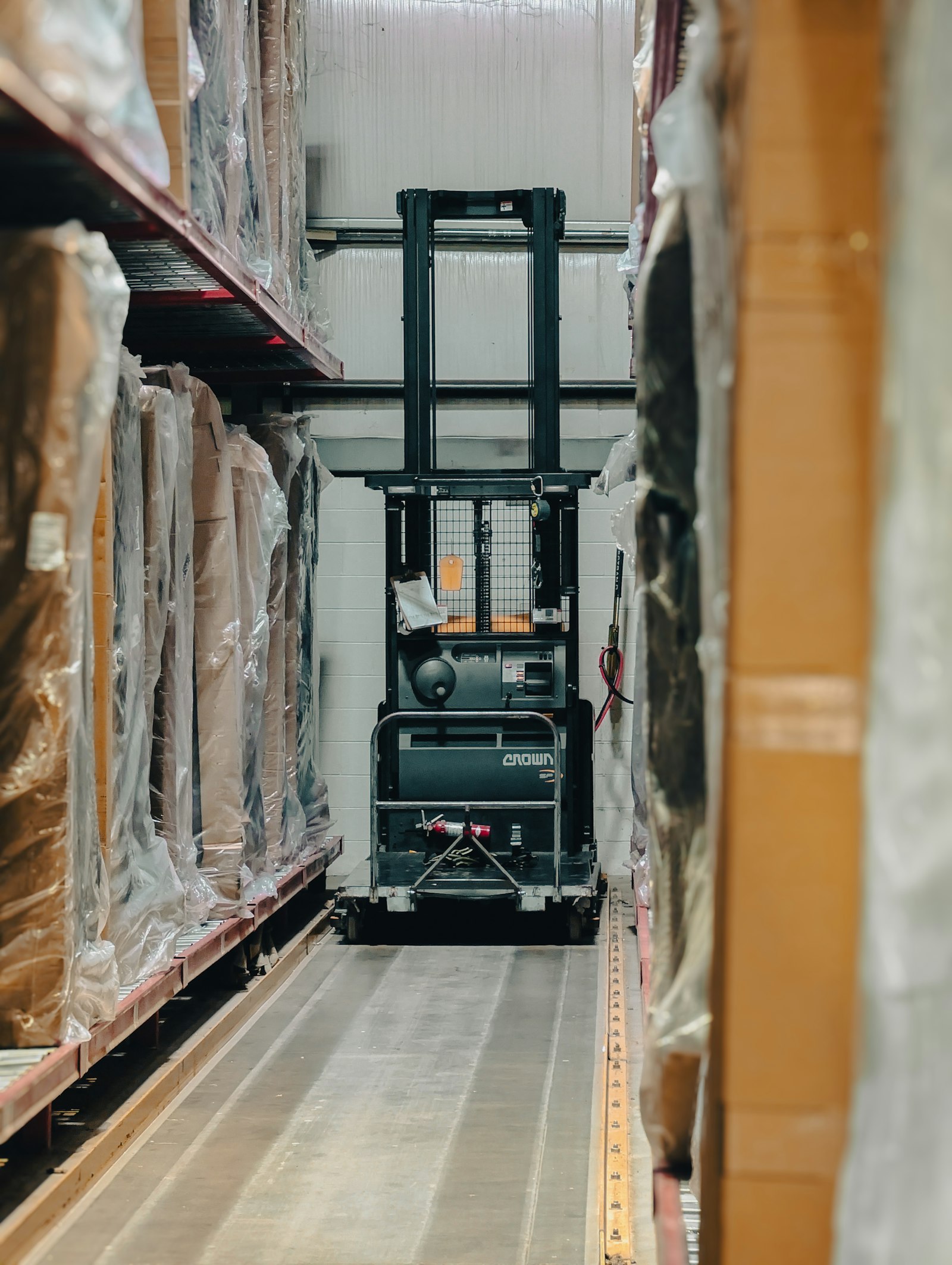 Forklift moving pallets between racked inventory inside a distribution warehouse